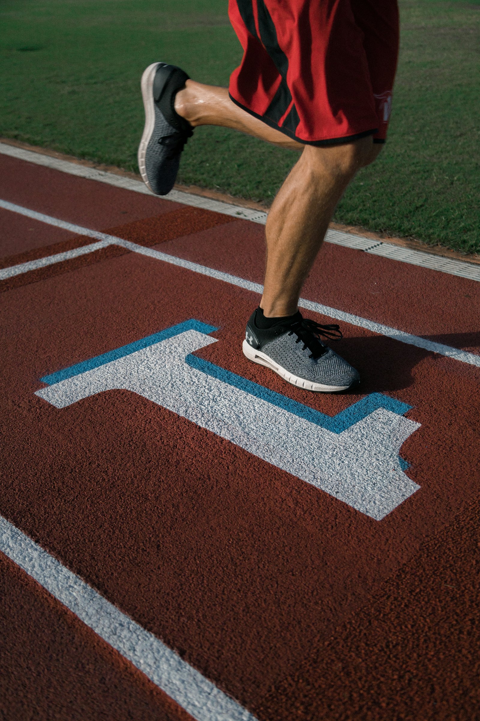 An athlete sprinting on a stadium track, mid-stride.